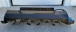 Black skid steer tiller side-on, rotor housing over a full row of curved tilling blades, blue drive motor at the right end