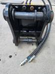 Black mounting bracket with upper and lower pins fitted, hydraulic hoses running out to the couplers