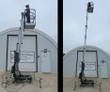 JLG push-around man lift with mast raised and an operator in the platform, outriggers set on the ground