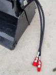 Bucket's side plate and jaw edge, two braided hoses running out to red-capped quick couplers