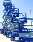 Genie GS-1930 scissor lifts in blue lined up in a row, platforms raised at staggered heights on their scissor stacks