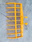 Yellow excavator rake from above, curved tines on a tubular frame with side-mounted pin bosses