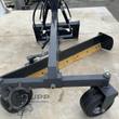 Landhonor grading blade from behind: black moldboard with yellow cutting edge, gauge wheels and quick-attach frame