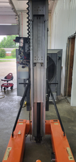 JLG 12SP from behind: aluminum telescoping mast with coiled cable, orange base and outrigger legs