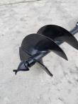 Auger bit head close-up: two black steel flights, cast pilot point and twin cutting teeth