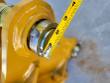 Pin, retaining bolt and bushing in the yellow mounting bracket, tape measure alongside reading about 3 inches