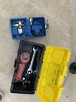 Accessory cases opened out: hydraulic pressure gauge, fittings and hose in one, wrench and hardware in the other
