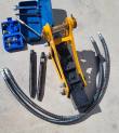 Yellow hydraulic breaker with two chisels, hoses, tool box and nitrogen charging kit laid out