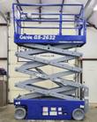 Blue Genie GS-2632 scissor lift partly raised on its scissor stack, guardrails and platform controls, non-marking wheels