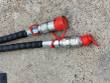 Two hydraulic quick-connect couplers with red dust caps on the bucket's hose ends