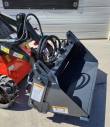Gray 4-in-1 bucket mounted on an orange mini skid steer, serrated clamshell jaw, hoses and warning decals