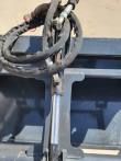 Hydraulic cylinder rod and sleeved hoses on the grapple bucket's gray frame