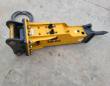 SB40 hydraulic breaker, yellow body with SB40 decal, black top mount, brass pins and coiled hoses