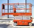 Orange Snorkel S3219E scissor lift, fully lowered, guardrails around the platform and the slide-out extension deck
