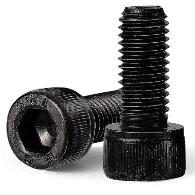 Two black oxide socket head cap screws, one showing the hex socket and 12.9 grade stamp on the head