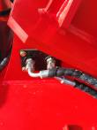 Hydraulic bulkhead fittings bolted to the red mulcher housing, spiral-wrapped hoses running out