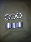 Six steel cylinder pin bushings, three showing bores and three showing machined sides