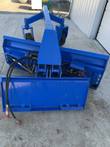 Blue 6-way dozer blade grader, rear view showing angling arms, caster wheels, and skid steer quick-attach plate