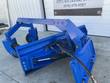 Blue 6-way dozer blade grader, front-angle view showing pivot arms, caster wheels, and hydraulic tilt cylinder