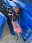 Corner of the dozer blade at the pivot mount, hydraulic hoses routed to the angling cylinder