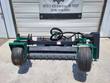 Soil conditioner front-on: carbide-tooth drum between two green gauge wheels, hydraulic drive motor at right