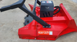 Mulcher attachment rotor underside with rows of flail teeth, raised on a loader arm outdoors