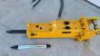 Yellow SB45 hydraulic breaker from above, moil chisel fitted, bracket pins and bushings, spare chisel and hoses