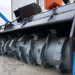 Drum mulcher rotor up close: spiral rows of bolt-on cutting teeth on the gray anti-wind drum under the deflector