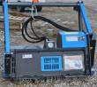 Raytree drum mulcher, blue motor housing with pressure gauge and warning labels over the toothed drum