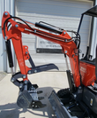 MX15R mini excavator boom, arm and toothed bucket with thumb, orange steel with hydraulic cylinders and hoses