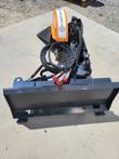 Wolverine stump grinder with orange housing and black frame, hydraulic hoses and fittings visible