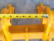 Tape measure across the yellow excavator rake's twin pin-boss mounts, spanning about 7 inches