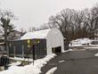 Container shelter spanning two shipping containers in snow, white front wall panel partly open