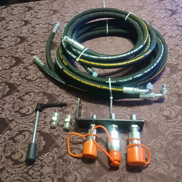 Auxiliary hydraulic kit: coiled hoses, three-coupler bracket with orange caps, control lever and adapters