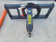 Auger drive unit on its universal quick-attach frame: hex output shaft, hoses with couplers, warning decals
