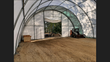 Interior of a fabric building with a skid steer parked near the back doorway