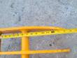 Tape measure laid along the yellow rake's curved tine, scale running past 15 inches