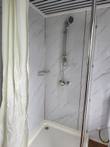 Shower corner with handheld shower head on slide rail, mixer valve and wire soap basket on marble-look walls