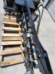 Wolverine trencher chain teeth close-up, warning decal, mounted on shipping pallet