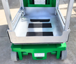 Genie GR-20 platform deck up close: aluminum floor with black grip strips, guardrails, green base on solid tires