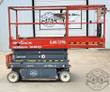 Red Skyjack SJIII 3219 scissor lift, side view fully lowered, guardrails around the platform and non-marking wheels