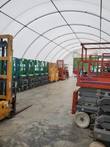Fabric building interior: white PVC cover on arched steel ribs, clear span over concrete floor lined with stored lifts