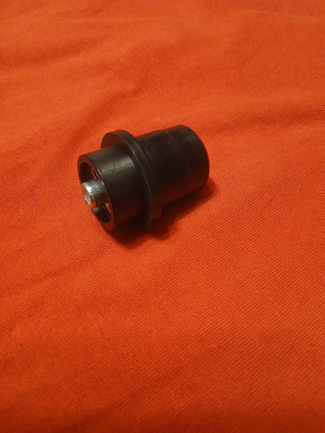 Black hydraulic filter bypass valve body with flange and a small steel stem visible in the open end