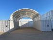Container roof shelter: white PVC arch on a steel frame spanning two shipping containers, open drive-through ends