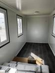 Portable office interior with white insulated wall panels, three windows and dark wood-look floor