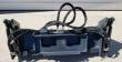 4-in-1 bucket from the rear, off the machine: quick-attach mount plate, twin clamp cylinders and sleeved hydraulic hoses