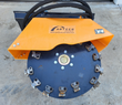 Arteer stump grinder wheel with bolt-on carbide teeth around the rim, under its orange debris shield and hoses