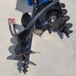 Three black auger bits on the hydraulic drive unit with red-capped hydraulic quick-connect couplers