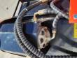 Flail mower's hydraulic drive motor bolted to the deck, sheathed hoses and elbow fittings running to it