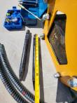 Two black chisels laid beside a tape measure, next to the yellow breaker's mount bracket